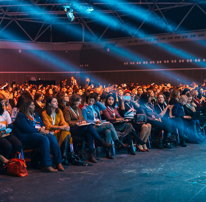 Large seated audience under blue lighting