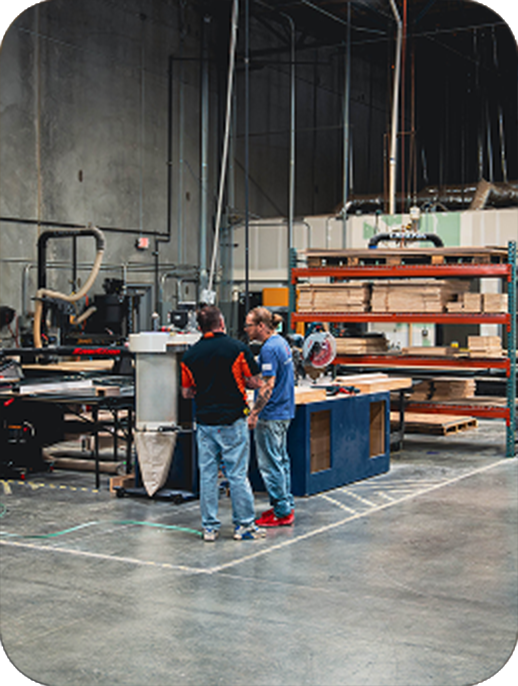 Two men talking inside a trade show fabrication shop