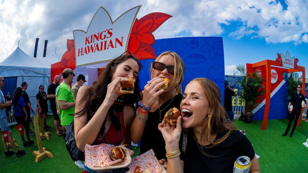 Guests enjoying King’s Hawaiian booth with branded backdrop at Super Bowl fan event