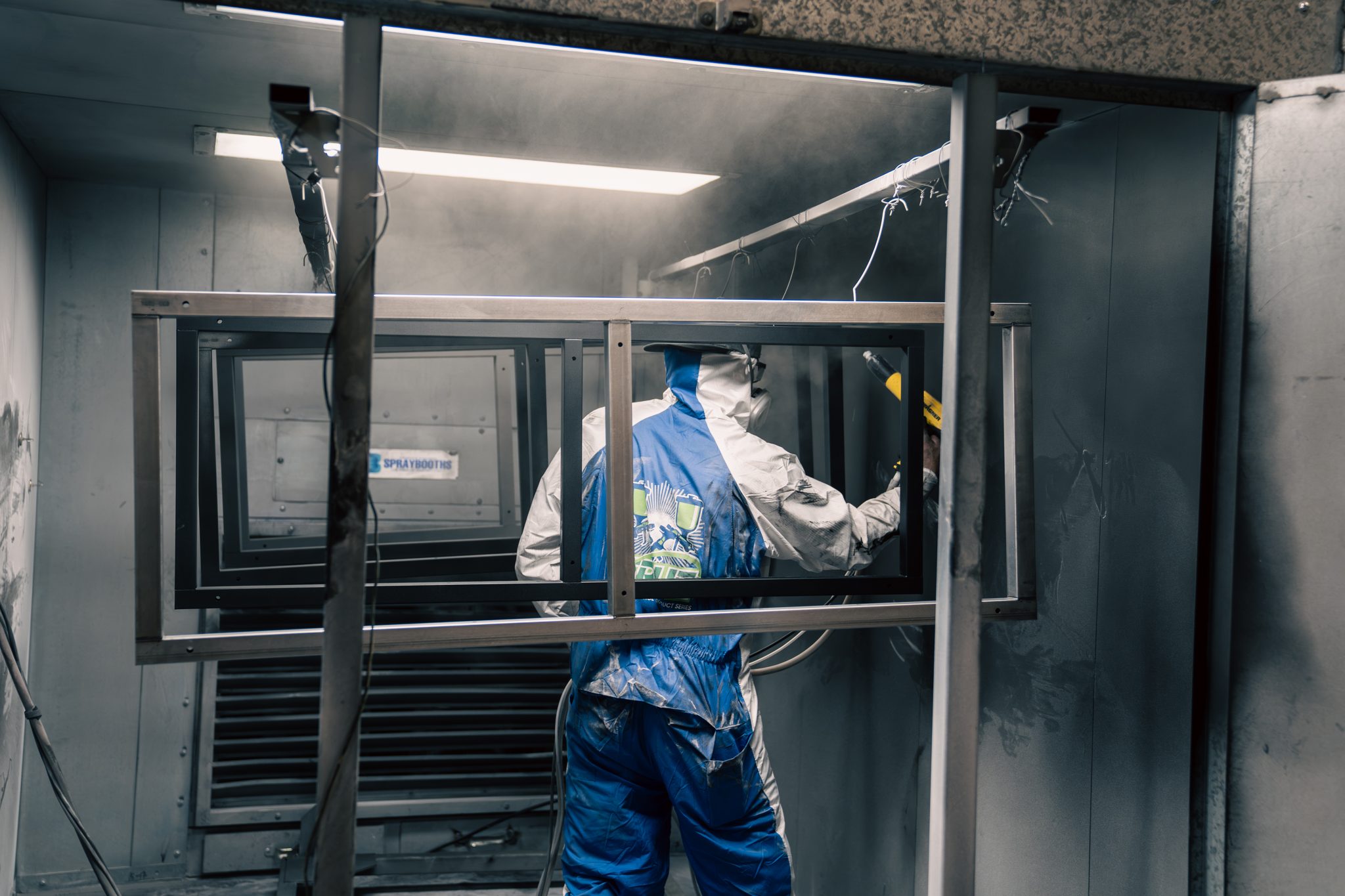 Powder coating a welded steel frame inside the spray booth